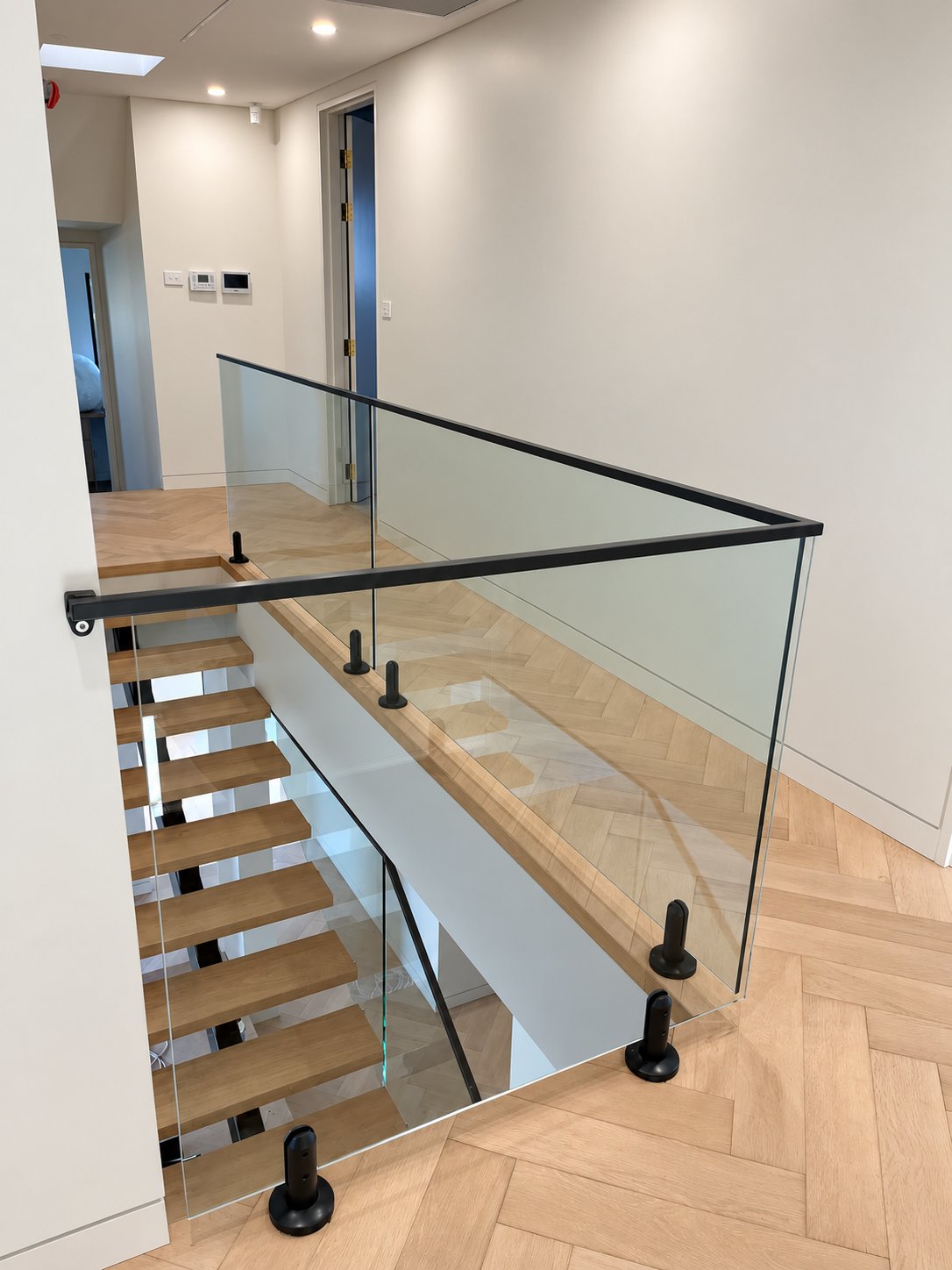 Welded square top rail returning around the upper landing to the wall handrail - New staircase glass with welded top rail - Strathfield