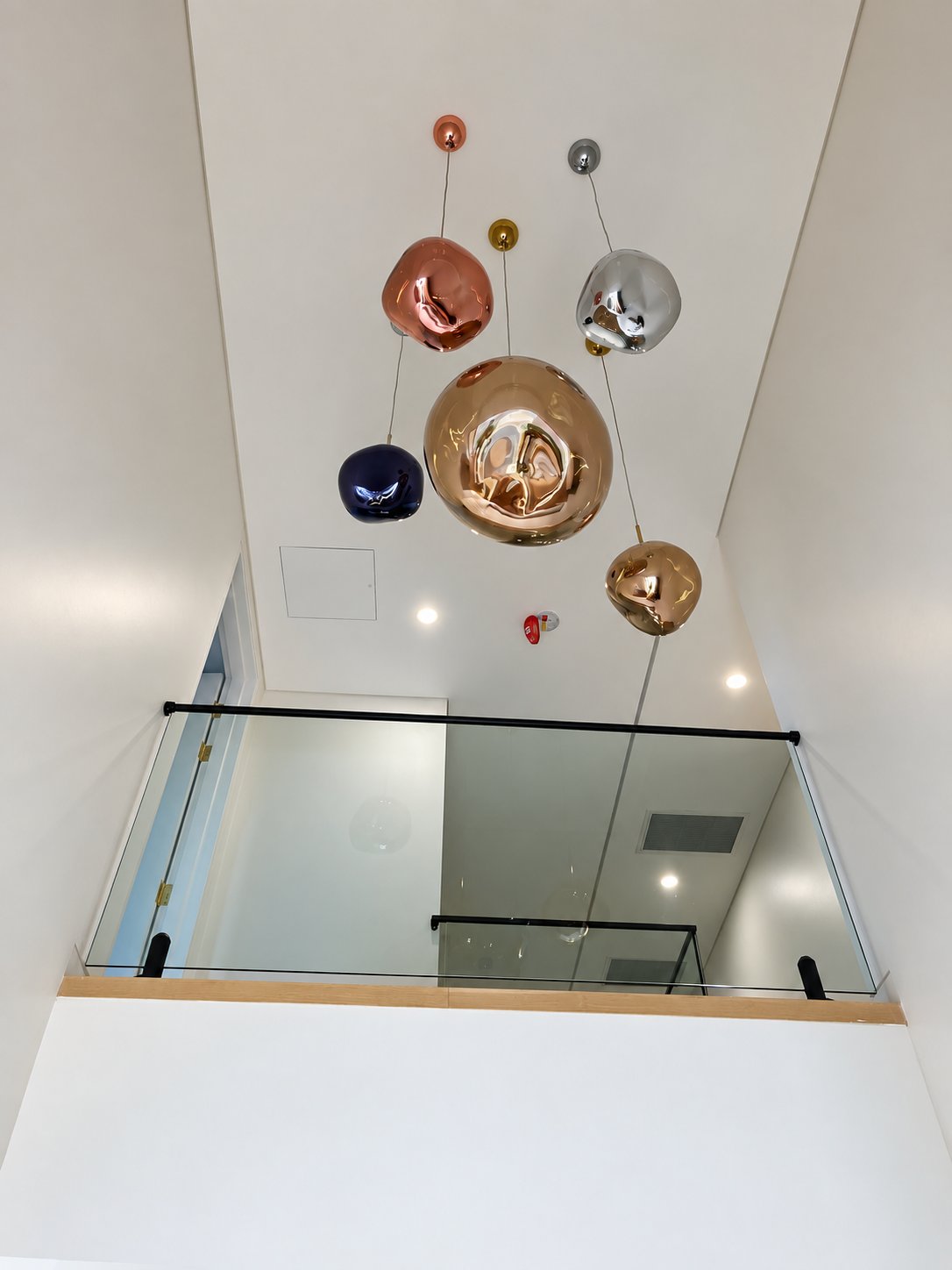 The void balustrade from below, under the pendant cluster - New staircase glass with welded top rail - Strathfield