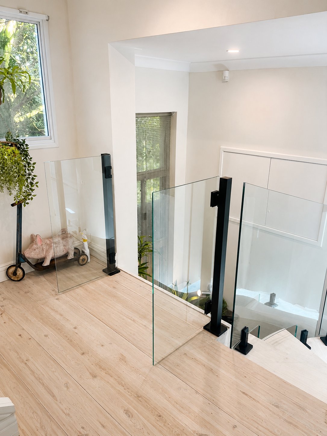 Landing view - the two glass access doors to the lift and the curved panel dropping down the stair - Curved stepped glass with lift access doors - East Ryde